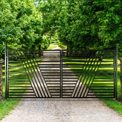 Stylish driveway gate framed by lush greenery and a gravel path